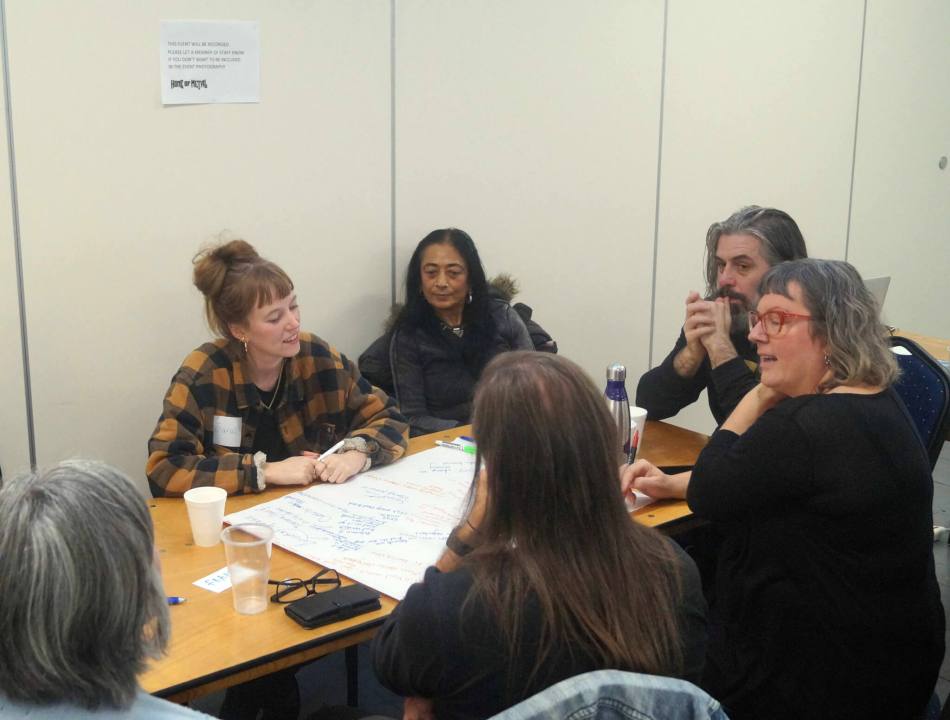 A photograph of a group of people in a round table discussion.