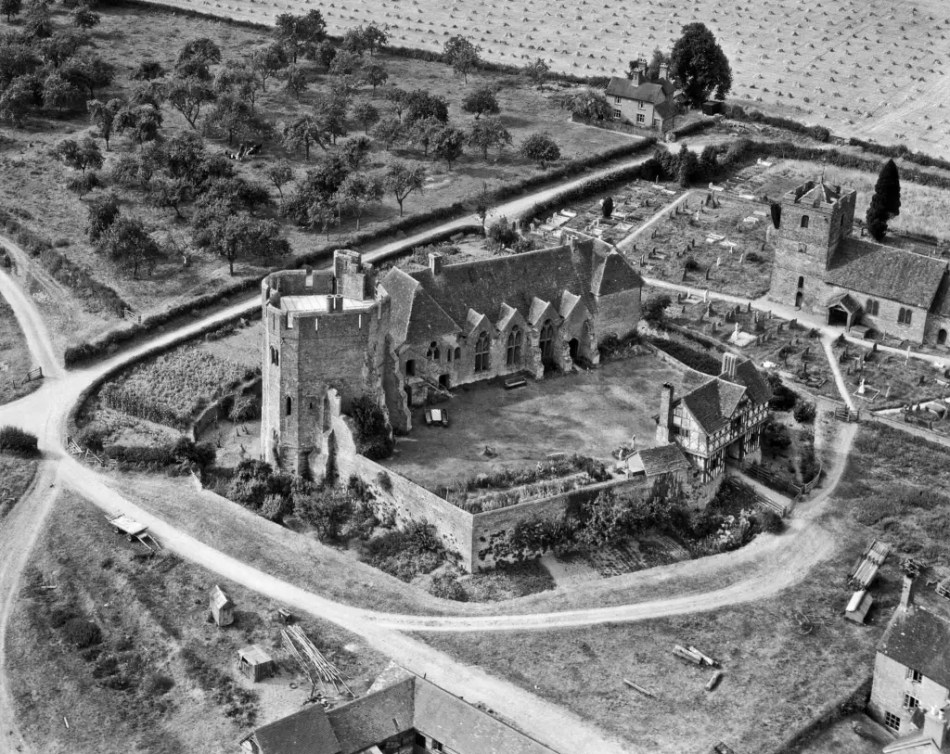A black and white aerial photograph of a castle with a timber-framed gatehouse.