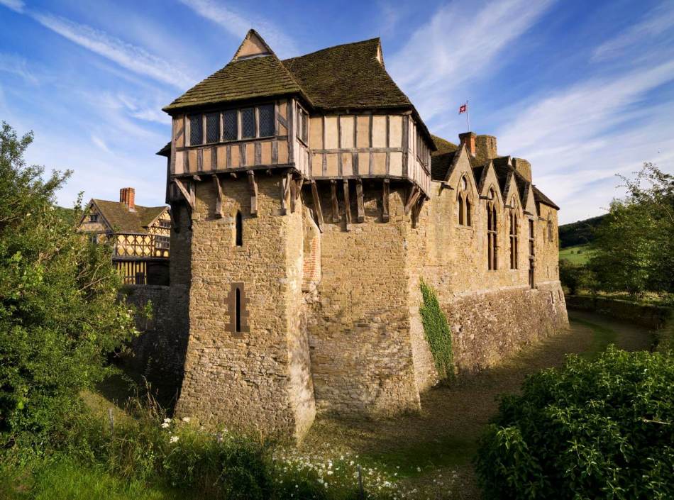 A photograph of a stone castle wall with a timber-framed building on the top storey.