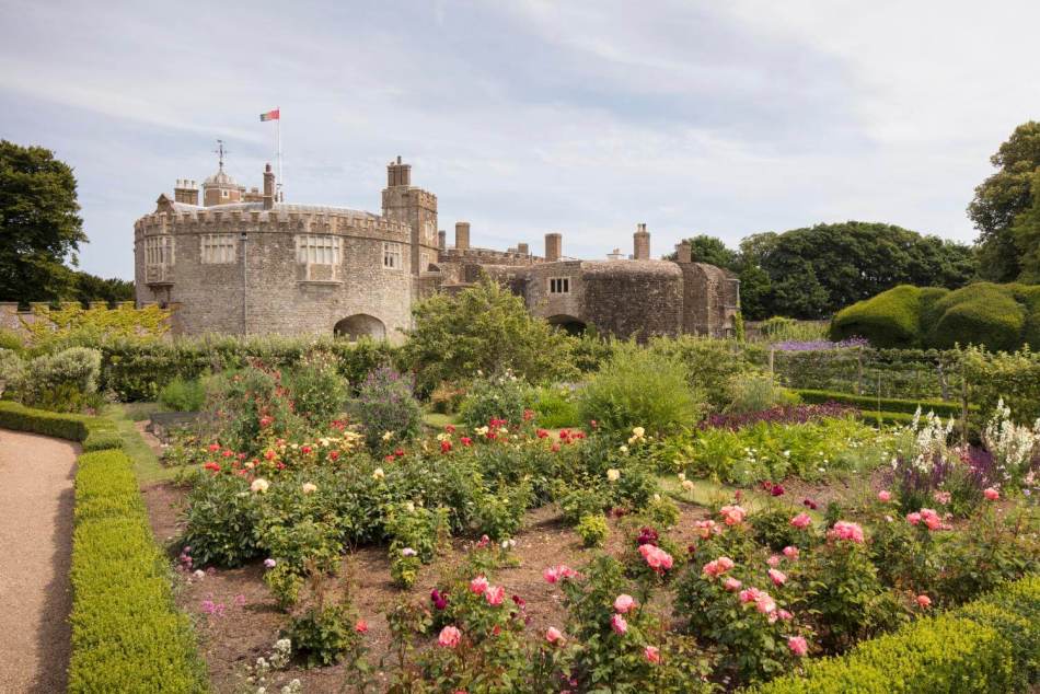 A photograph of a rose garden with a castle in the background.