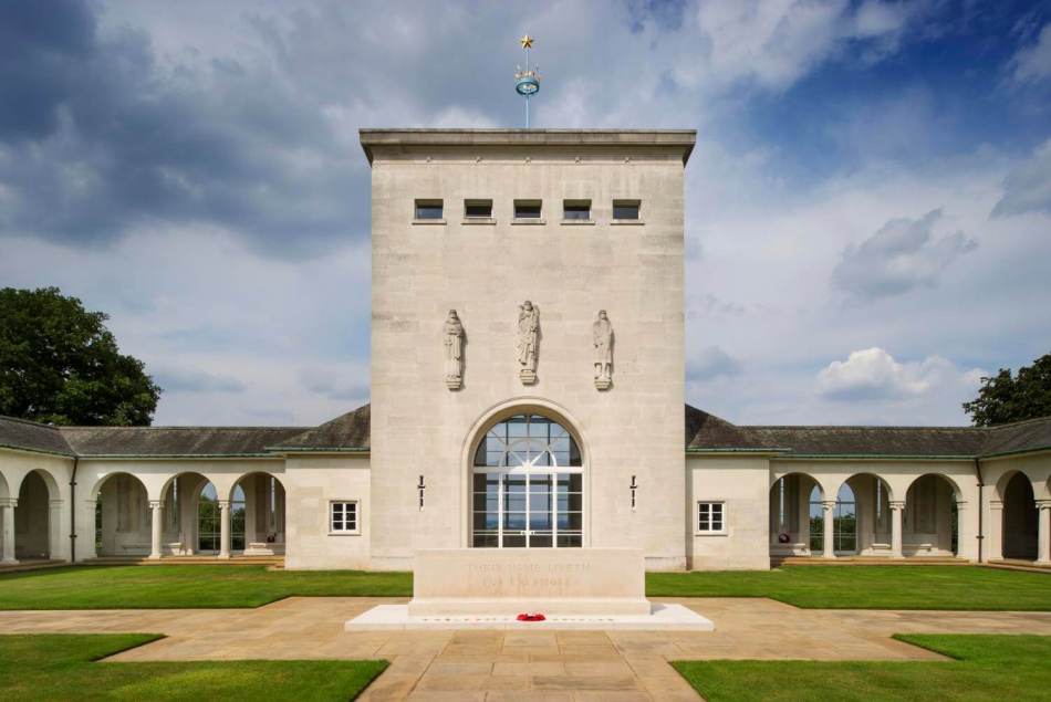 A photograph of the exterior of a large memorial building with 3 statues in the middle of the building, above an arched window.