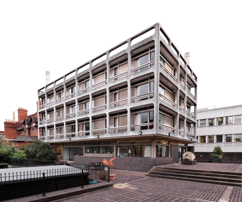 A photograph of a 4 storey concrete brutalist building. 