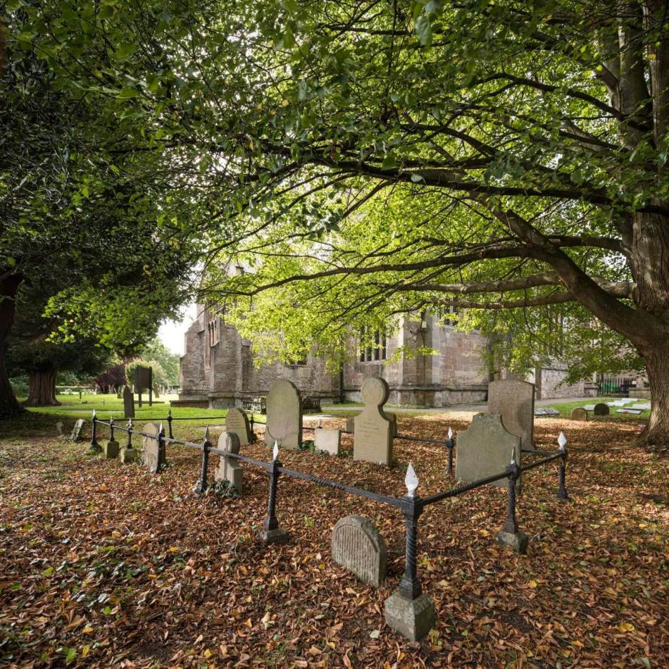 A photograph of multiple gravestones within a churchyard.