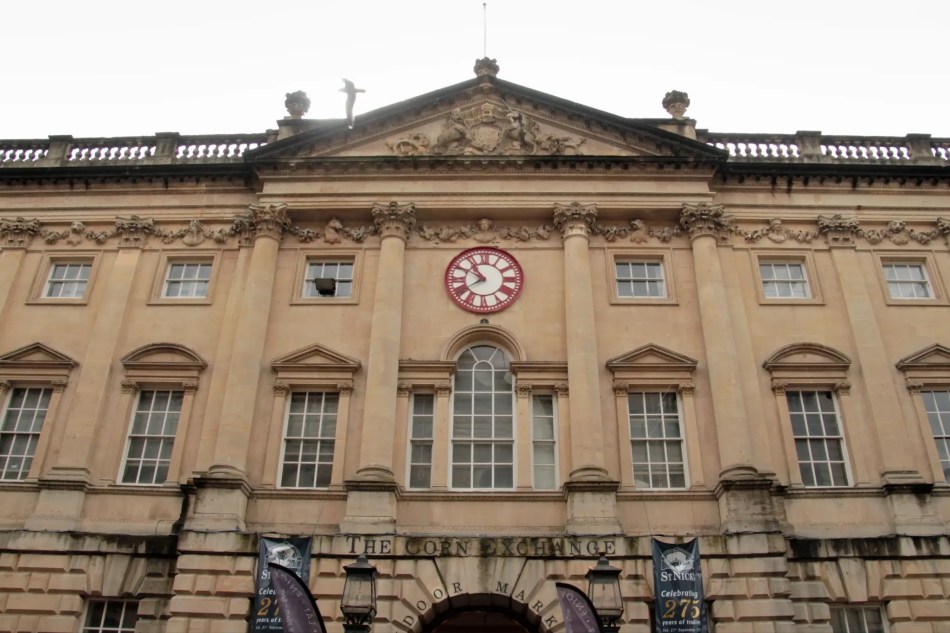 A photograph of a large, classical-style building with a clock at the centre.