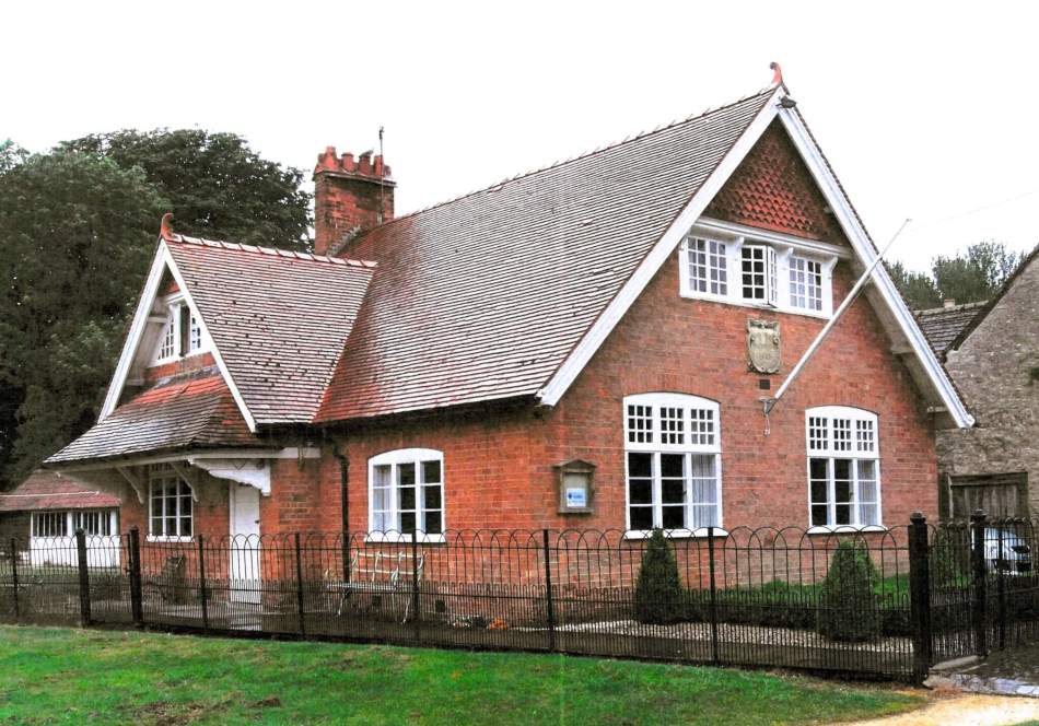 Red brick 2-storey building with a steep tiled roof. There is a 2-storey porch to the left-hand elevation.