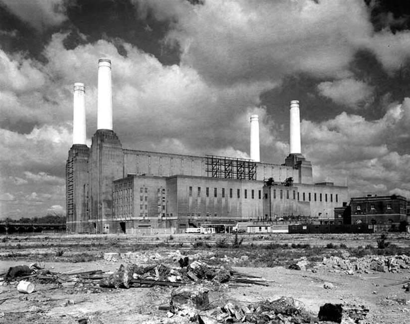 Black and white photo of Battersea Power Station viewed across rubble strewn ground.